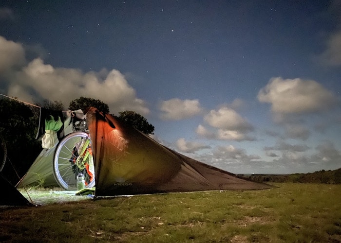 Bikepacking tent setup at night under a starry sky.